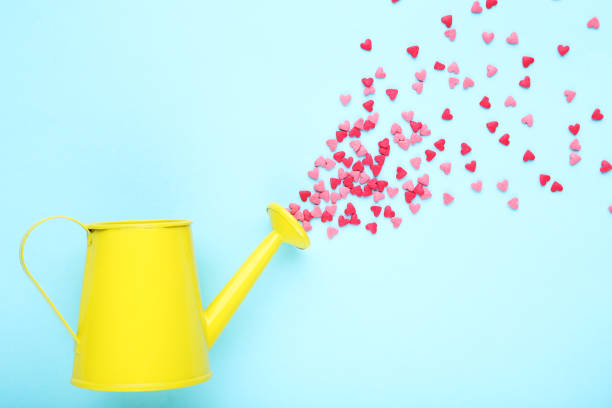 istock Heart shaped sprinkles with watering can on blue background 1200062535