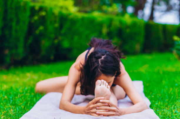 istock Girl practicing yoga while sitting by the green grass. 1200063704