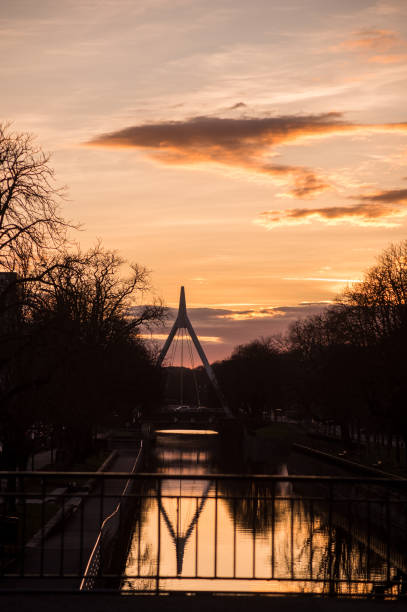 silhouette of suspended bridge under the channel with reflection by sunset panorama with silhouette of suspended bridge under the channel with reflection by sunset mulhouse photos stock pictures, royalty-free photos & images