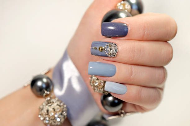 Fashionable grey blue manicure on square shaped nails.Nail art with rhinestones on a light background with decoration.