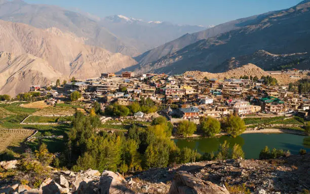 Nako village flanked by fields, high Himalayan mountains, and popular lake in the Spiti valley at sunrise in Himachal Pradesh, India.