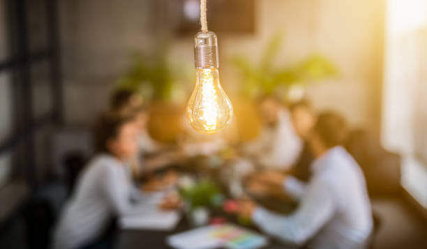Young creative business people meeting at office. Young business people are discussing together a new startup project. A glowing light bulb as a new idea. market research photos stock pictures, royalty-free photos & images