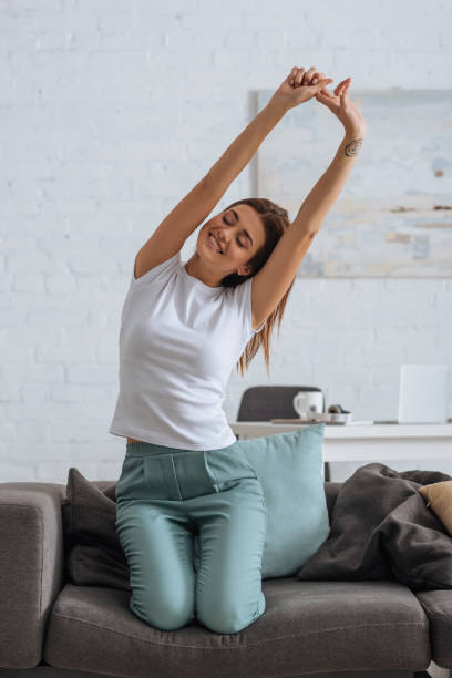 istock smiling woman stretching while chilling on sofa in living room 1200079009