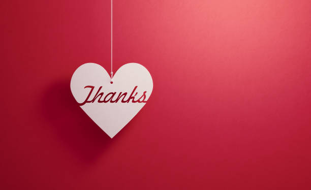 Thanks written white heart shape hanging over red background, Horizontal composition. Thank you concept.