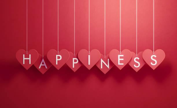 istock Happiness Writes over Red Heart Shapes Hanging over Red Background 1200081016