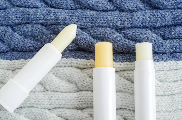 Three lip balms on the knitted background. Winter lip care sticks with beeswax, honey, panthenol and shea butter. Copy space. Three lip balms on the knitted background. Winter lip care sticks with beeswax, honey, panthenol and shea butter. Copy space. vitamin b 3 stock pictures, royalty-free photos & images