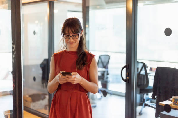 istock Young woman texting in front of her office 1200083561