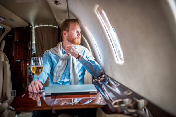 joven hombre exitoso bebiendo vino y disfrutando mientras viaja con un avión privado - status symbol audio fotografías e imágenes de stock