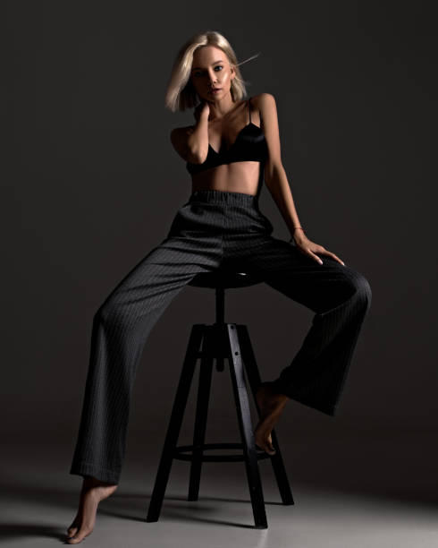 stylish fashion elegant blonde woman model posing on black background in underwear and classic trousers. confident girl with beautiful face and body portrait in lingerie in room - fato de senhora imagens e fotografias de stock