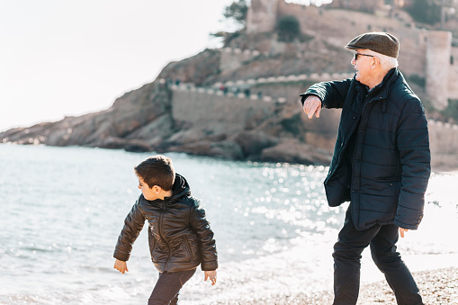 Grandfather and grandson throwing rocks on the beach