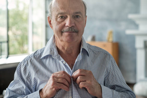 Senior caucasian hispanic man in the white shirt buttoning shirt up at morning. Senior caucasian hispanic man in the white shirt buttoning shirt up at morning. Studio shot buttoning stock pictures, royalty-free photos & images