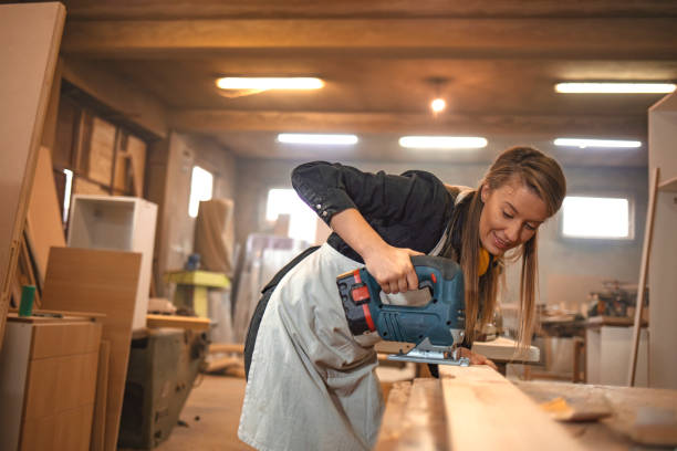 istock Attractive female carpenter using some power tools for her work in a woodshop. 1200093391