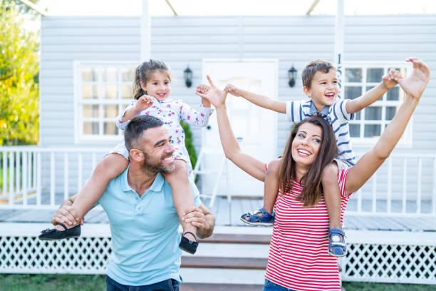 istock Parents having fun in front yard carrying children piggyback 1200094641