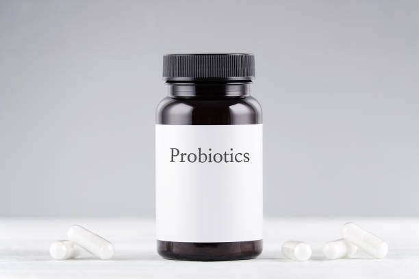 nutritional supplement probiotics bottle and capsules on gray a black jar with probiotics and capsules on gray background probiotic photos stock pictures, royalty-free photos & images