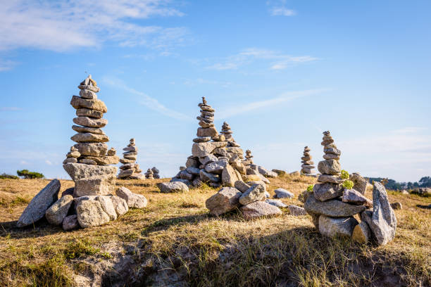 Cairns by the seaside on a sunny day. Many man-made granite stone stacks (called cairns) on the coastal path in Brittany, France, on a sunny late afternoon. cairn stock pictures, royalty-free photos & images