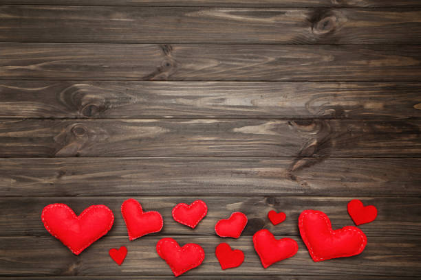 istock Red fabric hearts on brown wooden table 1200097855