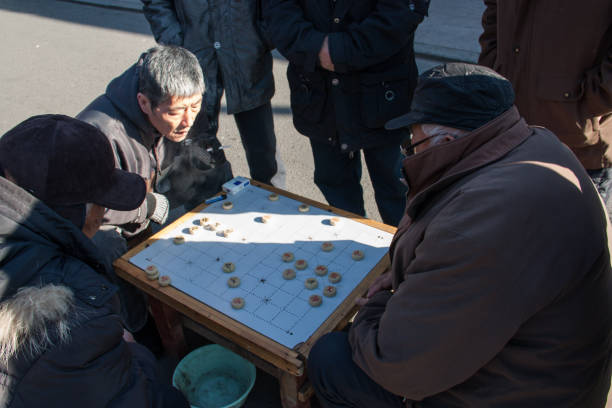 les hommes aînés jouent aux échecs chinois dans la rue en hiver. - chinese chess leisure games chinese culture traditional culture photos et images de collection