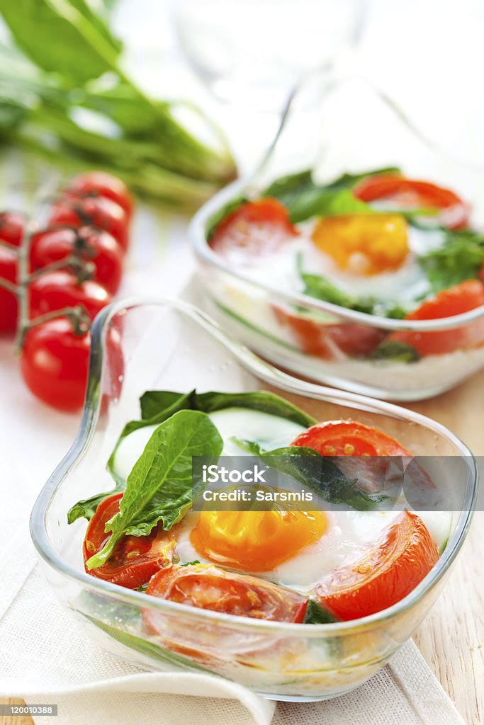 Baked eggs Baked eggs with tomatoes and spinach  Appetizer Stock Photo