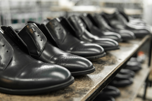 A lot of new black shiny shoes on a shelf. Shoe factory, finished goods warehouse
