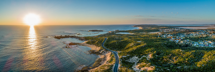 Scenic drive passing near ocean coastline and Beachport town at sunset - wide aerial panorama