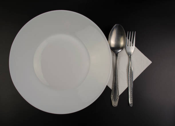 istock White plate and iron cultery lie on a black table 1200105982