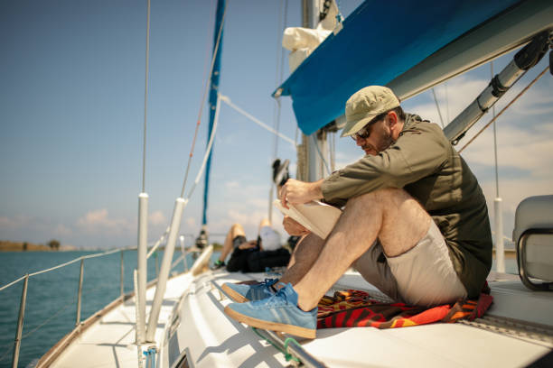istock Man reading book on sailboat 1200108915