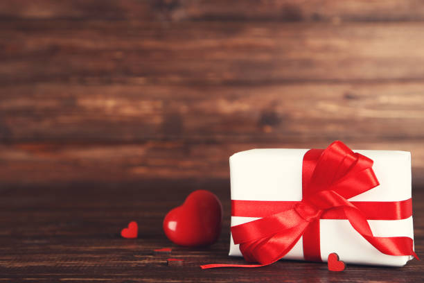 istock Gift box with ribbon and hearts on brown wooden table 1200109295