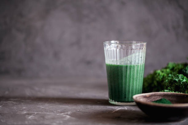 ein glas gesunde vegane trinken grün grünkohl smoothie mit spirulina für entgiftung auf dunklem hintergrund - chlorophyll green smoothie smoothie vegetable stock-fotos und bilder