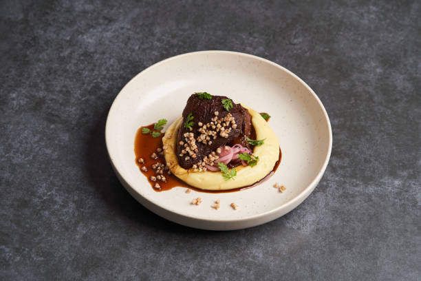 istock Stewed veal cheeks with mashed potatoes on a white plate, close-up. 1200112003