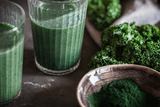 ein gesundes veganes getränk grünkohl smoothie mit spirulina für entgiftung auf dunklem hintergrund - chlorophyll green smoothie smoothie vegetable stock-fotos und bilder