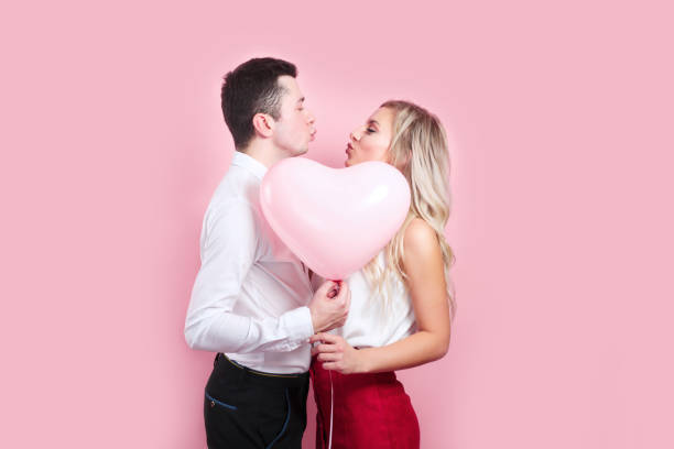 istock Couple covering faces with balloon on pink background 1200112138