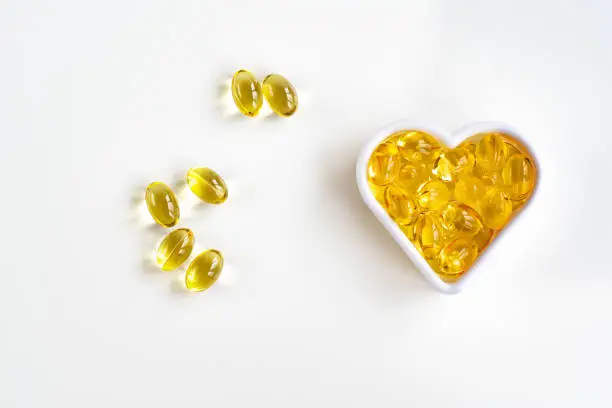 Photo of Omega-3 fish oil capsules in the shape of a heart for the cardiovascular system of the body. View from above