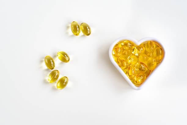 cápsulas de óleo de peixe ômega-3 na forma de um coração para o sistema cardiovascular do corpo. vista de cima - vitamin e capsule vitamin pill cod liver oil - fotografias e filmes do acervo