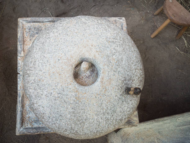 istock Rotary discoid mill stone for hand-grinding a grain into flour. Medieval hand-driven millstone grinding wheat. The ancient Quern stone hand mill with grain. 1200116280