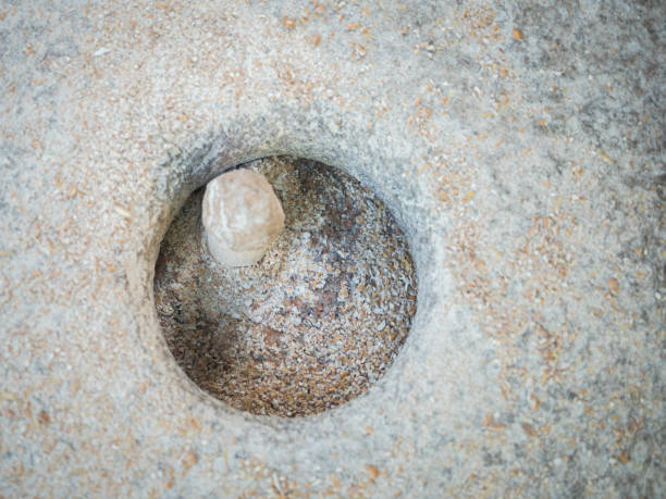 istock Rotary discoid mill stone for hand-grinding a grain into flour. Medieval hand-driven millstone grinding wheat. The ancient Quern stone hand mill with grain close up. 1200116299
