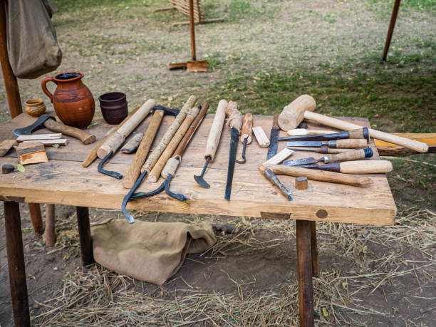 Old woodworking hand tool: wooden plane, chisel ax, sledgehammer, hammer and in a carpentry workshop on dirty rustic table covered with sawdust background side view.