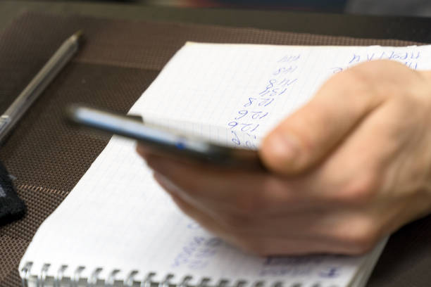 A man holds a smartphone against a sheet of paper