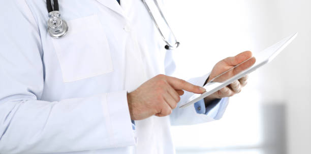 istock Doctor man using tablet computer for network research or virtual disease treatment, hands close-up. Perfect medical service in clinic. Modern medicine, medic data and healthcare concepts. Toned picture 1200122843