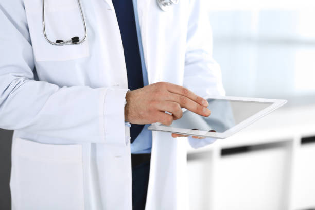 istock Doctor man using tablet computer for network research or virtual disease treatment, hands close-up. Perfect medical service in clinic. Modern medicine, medic data and healthcare concepts. Toned picture 1200122875
