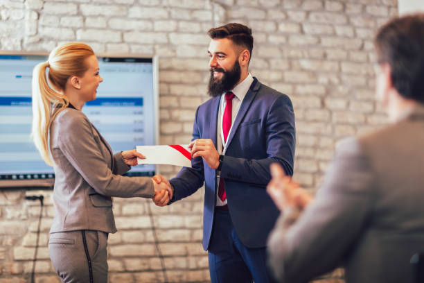 Man receiving award from businesswoman Front view of businessman receiving award from businesswoman in front of business professionals applauding at business seminar in office building receiving stock pictures, royalty-free photos & images