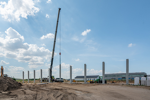 on a construction site, concrete columns for a factory building are placed with the help of a large crane