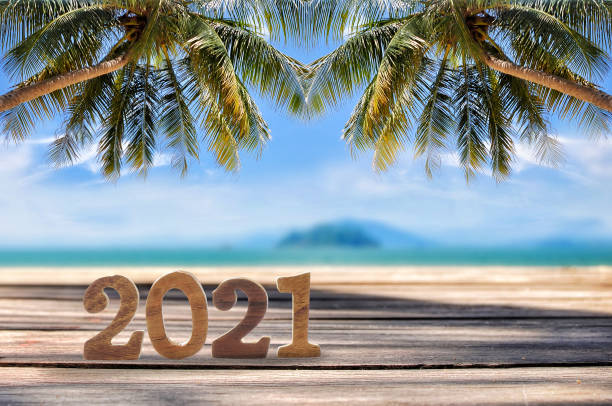 Wood cube number 2021 on planks on tropical beach background