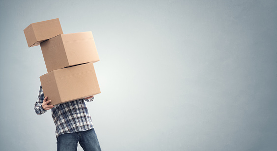 Hombre sosteniendo pesadas cajas de cartón reubicación, mudanza de la casa o entrega de mensajería photo