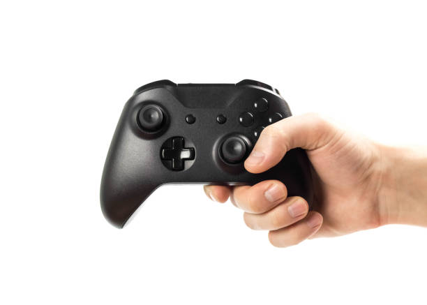 istock The hand holds a black gamepad for playing computer games. Isolated on a white background. Close up 1200124969