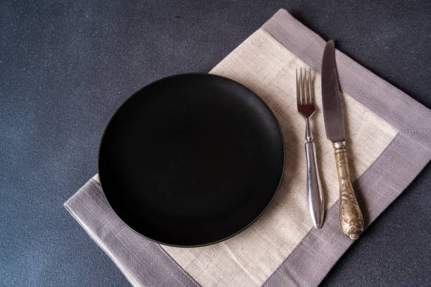 istock Black plate with napkin on stone table top view. space for menu or recipe. 1200127074