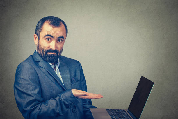 istock man showing pointing presenting a laptop screen with an open palm on grey 1200128683