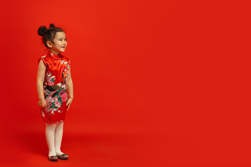 Posing confident and smiling. Happy Chinese New Year 2020. Asian cute little girl isolated on red background in traditional clothing. Celebration, human emotions, holidays concept. Copyspace.