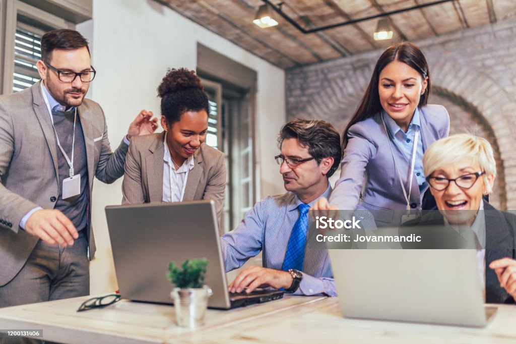 Lächelnder junger Manager hilft leitenden Angestellten bei der Computerarbeit im Büro - Lizenzfrei Frauen Stock-Foto