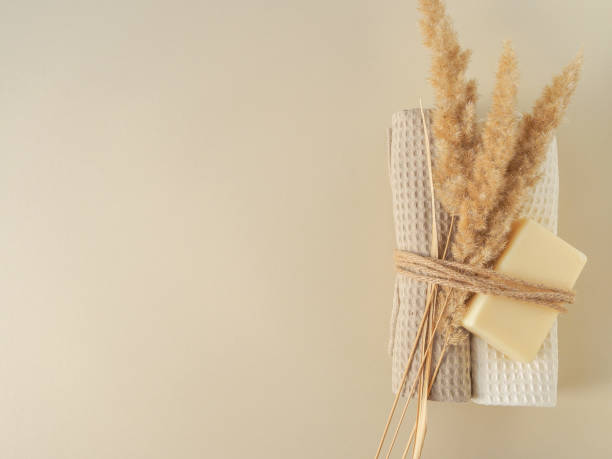jabón hecho a mano, toallas y plantas secas atadas con una cuerda sobre un fondo beige - jabonera fotografías e imágenes de stock
