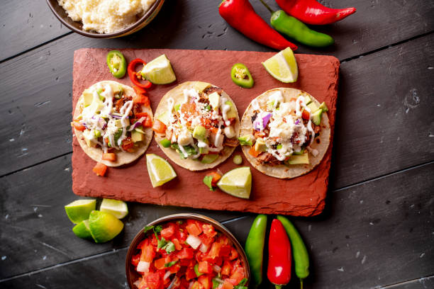 istock Pork Carnitas Tacos on a Rustic Slate Ready to be Served with Peppers, Lime, Salsa and Cotija Cheese 1200136340